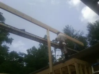 Carpenter setting a ridge beam over a new addition frame — Ice Dam Removal by Roofing Brothers in Jonas Ridge