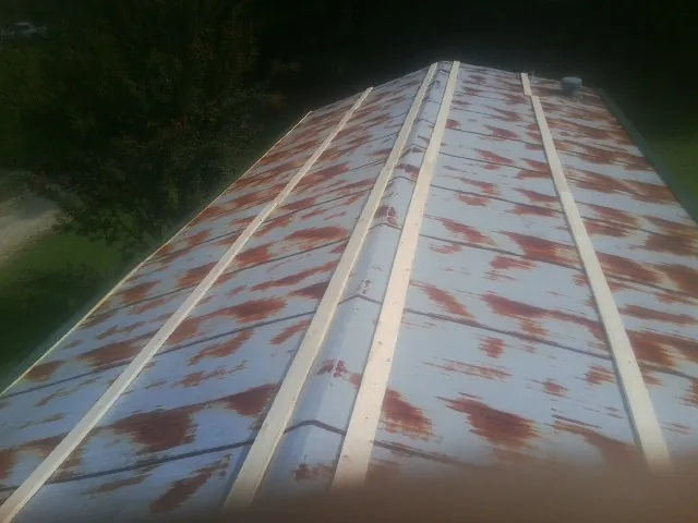 Rusted metal roof panels with new wood purlins before replacement — Storm Damage Roof Repair in Jonas Ridge by Roofing Brothers