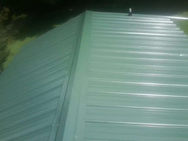New green metal panels meeting at the ridge of a roof — Flat Roof Repair work by our crew in Jonas Ridge