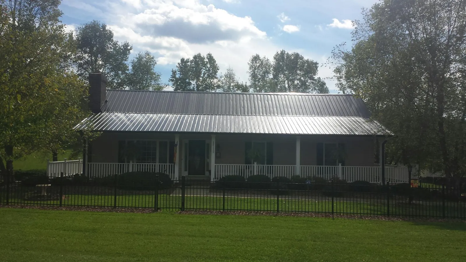 Gray metal roof on a brick ranch with a full width front porch — Gutter Guard Installation work by our crew in Jonas Ridge