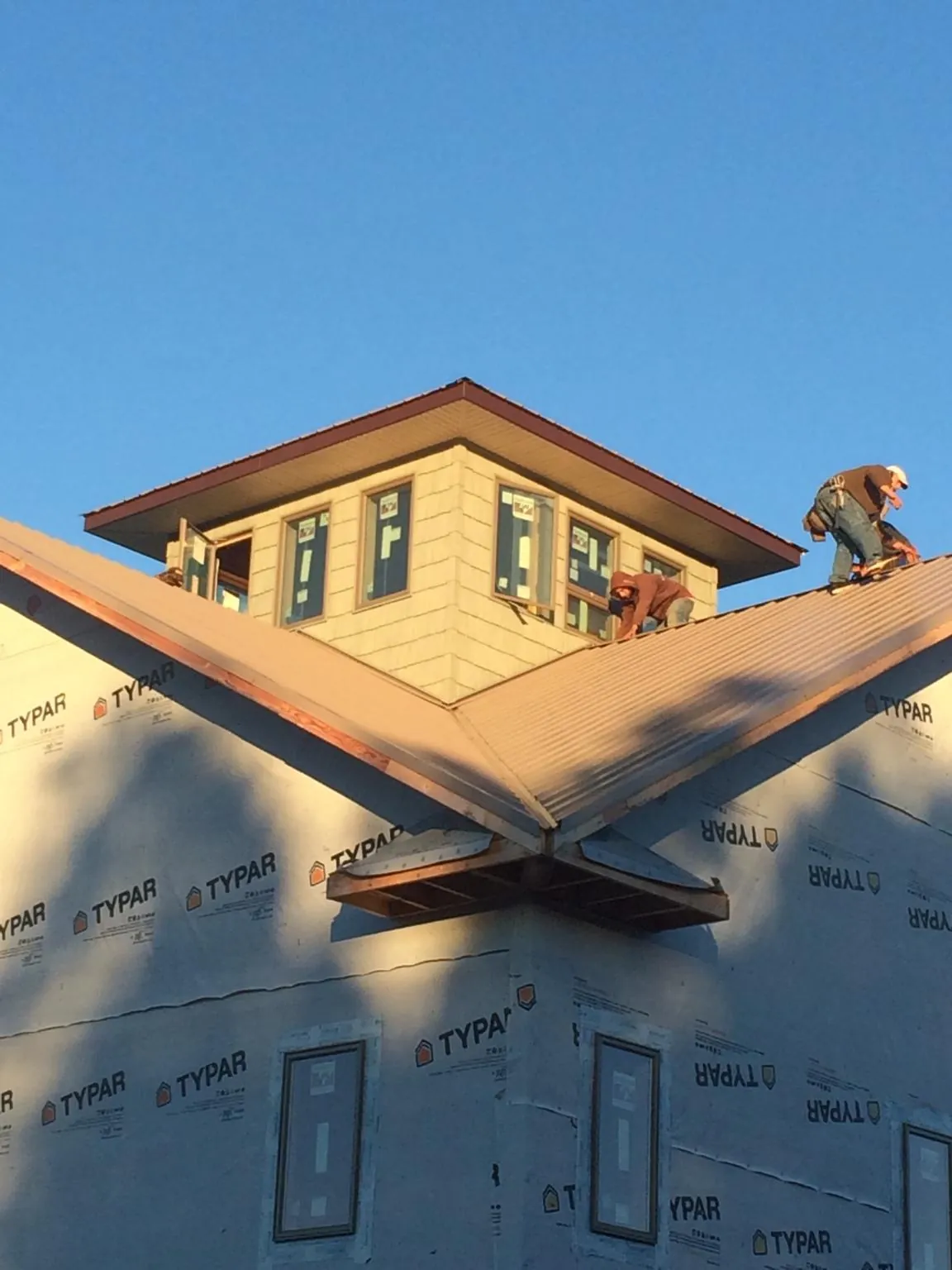 Roofers working around a rooftop cupola on a new metal roof at sunset — Roof Waterproofing in Jonas Ridge by Roofing Brothers